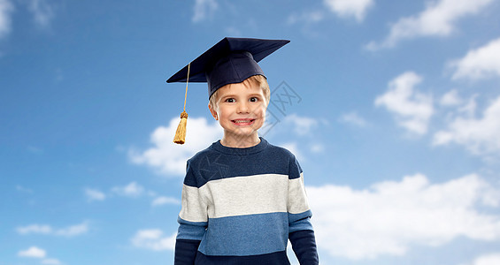 学校,教育学小男孩戴着学士帽或灰泥板蓝天云彩背景上戴着学士帽或灰泥板的小男孩图片