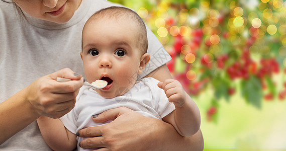 孩子,饮食食物的母亲与勺子喂养小婴儿夏季花园背景用勺子喂小宝宝来亲近妈妈背景图片