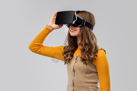 技术,增强现实娱乐快乐的少女与虚拟耳机或VR眼镜灰色背景灰色背景下戴VR眼镜的十几岁女孩图片