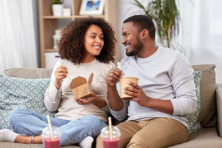 外卖食品,饮料人们的快乐的非裔美国人夫妇家用筷子吃炒锅幸福的夫妇带着外卖食品饮料家图片
