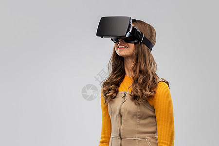 技术,增强现实娱乐快乐的少女与虚拟耳机或VR眼镜灰色背景灰色背景下戴VR眼镜的十几岁女孩图片