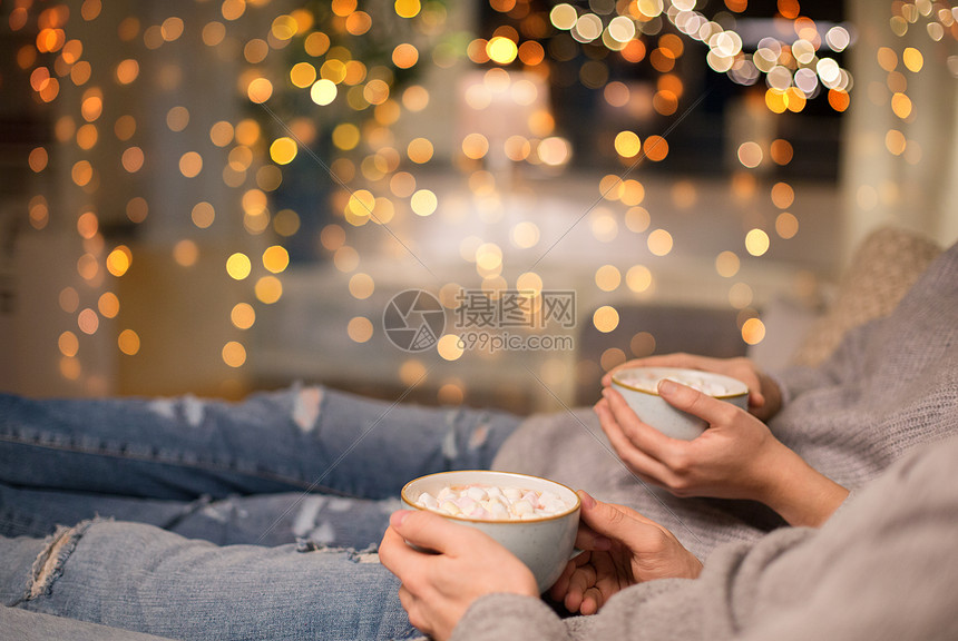 潮湿,休闲圣诞节的近距离的夫妇喝热巧克力与棉花糖家里闪烁的节日灯亲密的夫妇家里喝热巧克力图片