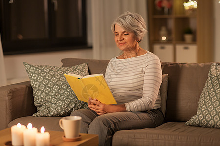 年龄休闲人的快乐的老年妇女晚上家看书快乐的高级妇女晚上家看书图片