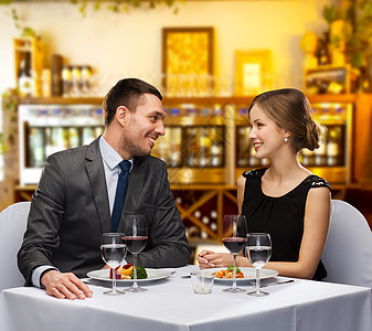 休闲奢侈的微笑的夫妇与食物葡萄酒餐厅或酒吧背景带着食物葡萄酒餐厅微笑的夫妇图片