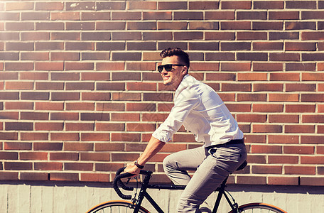 生活方式,交通人们的戴太阳镜的年轻人骑自行车城市街道上的砖墙年轻人骑自行车城市街道上图片