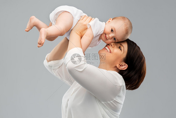 家庭孩子父母的快乐的微笑中年母亲抱着灰色背景的小女儿快乐的中年母亲小女儿图片