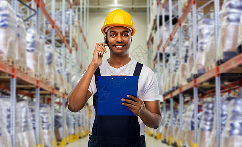 物流业务人的快乐的微笑印度装载机或工人头盔与剪贴板呼叫智能手机仓库背景印度工人仓库打电话给智能手机图片