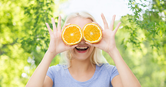 健康的饮食,食物,饮食人的快乐的微笑女人玩得开心,用橙色的切片覆盖她的眼睛绿色的自然背景上快乐的女人玩得很开心,用图片