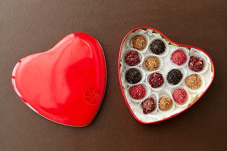 糖果,糖果食品糖果红色心形巧克力盒棕色背景红色心形巧克力盒里的糖果图片