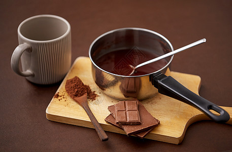 糖果,糖果烹饪锅与融化的热巧克力,可可粉勺子,陶瓷杯木板棕色背景锅里有热巧克力杯子可可粉图片