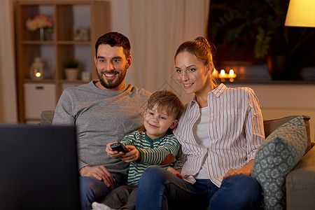 家庭,休闲人的快乐微笑的父亲,母亲小儿子与遥控器家里晚上看电视快乐的家人晚上家看电视图片