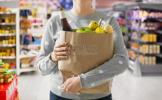 购物,健康饮食生态友好的妇女与纸袋充满食物超市的背景用装满食物的纸袋把女人关起来图片