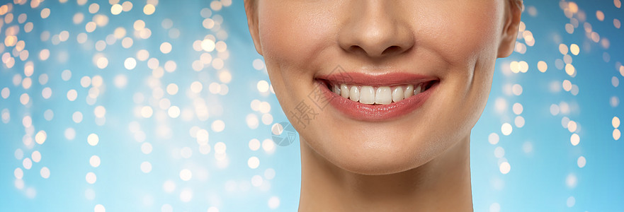 美容,牙科护理牙齿美白美丽的年轻女人与白色微笑的假日灯光蓝色背景用白色的微笑靠近美丽的年轻女人图片