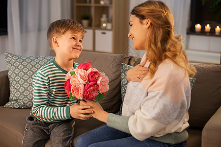 母亲节假期家庭观念快乐的小儿子晚上家给他的母亲送花微笑的小儿子家给妈妈送花图片