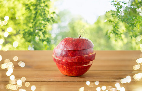 水果,食物收获的切片红苹果木制桌子上绿色自然背景木桌上的红苹果切片图片