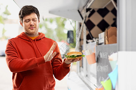 快餐,健康的饮食人们的年轻人穿着红色连帽衫,拒绝汉堡食品卡车街头背景年轻人拒品卡车上吃汉堡包图片