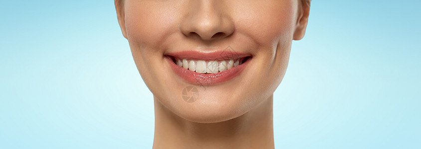 美容,牙科护理牙齿美白特写美丽的年轻女人的脸与白色的微笑蓝色的背景用白色的微笑靠近美丽的年轻女人图片