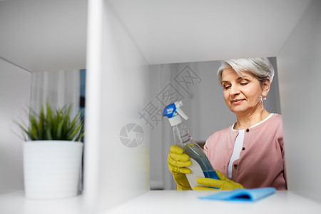 人,家务家务快乐的高级妇女清洁架阅读标签上的洗涤剂家里高级妇女清洁架与洗涤剂家里图片
