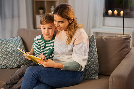 家庭休闲人的快乐微笑的母亲小儿子坐家里的沙发上看书快乐的母子家看书沙发图片