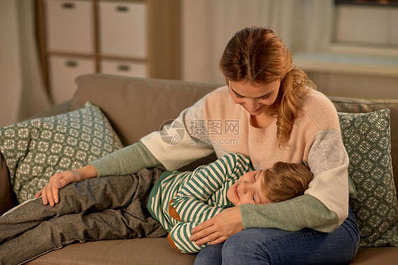 家庭爱人的快乐的微笑母亲小儿子晚上睡家里的沙发上快乐的母亲熟睡的小儿子家里图片