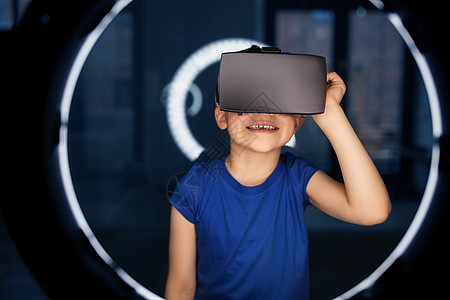 未来的技术人们的快乐的微笑男孩VR眼镜或虚拟现实耳机白色照明黑暗的房间男孩戴着VR眼镜,黑暗的房间里照明图片