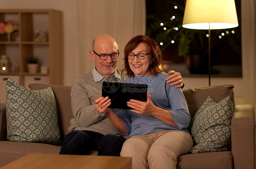 技术,老年人人的快乐的微笑老年夫妇与平板电脑家里晚上快乐的老年夫妇与平板电脑家图片