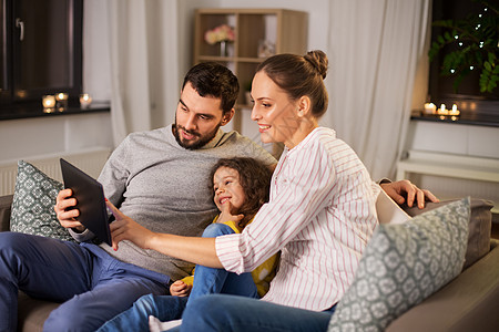 家庭,人技术的快乐的微笑父亲,母亲小女儿家里的平板电脑晚上晚上家里有平板电脑的幸福家庭图片
