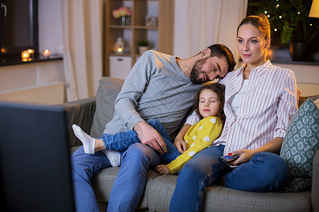 家庭,休闲人的父亲小女儿睡觉,而母亲晚上家看电视疲惫困倦的家人晚上家看电视图片