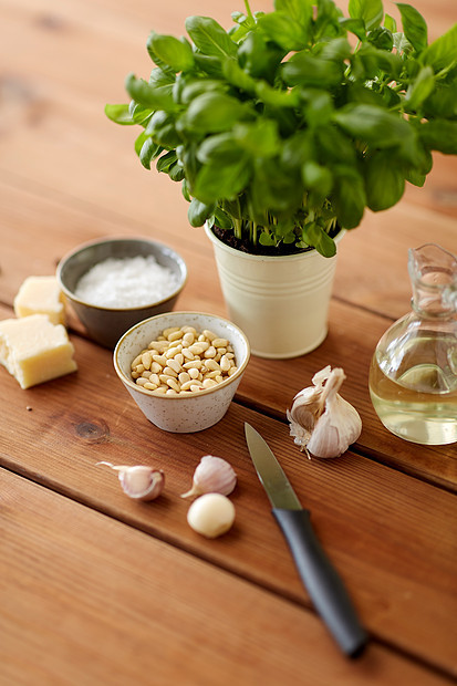 食物烹饪帕尔马干酪,松子,醋大蒜为罗勒虫酱木制桌子上制作木桌上罗勒酱的配料图片