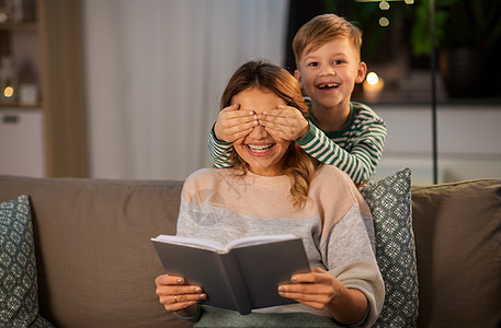 家庭,爱人的快乐的微笑母亲与她的小儿子晚上玩书游戏快乐微笑的母亲家里她的儿子玩耍图片