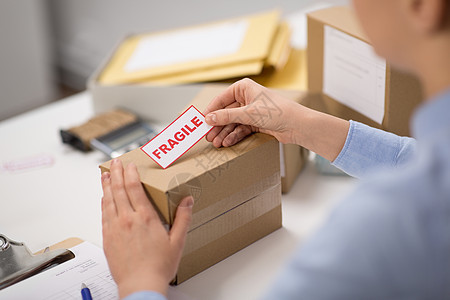 送货,邮件服务,人员装运妇女粘贴易碎标记的包裹盒邮局女人把易碎的标记贴包裹箱上图片