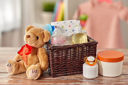婴儿期护理产品的婴儿的东西柳条篮子泰迪熊玩具木制桌子家里篮子里的婴儿用品桌子上的泰迪熊玩具图片