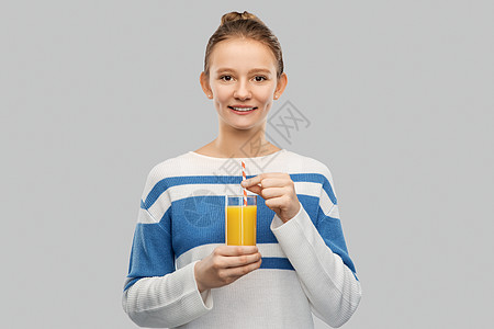 人们的快乐微笑的十几岁女孩穿着套衫,着杯橙汁,背景灰色的纸吸管微笑的少女着杯橙汁图片