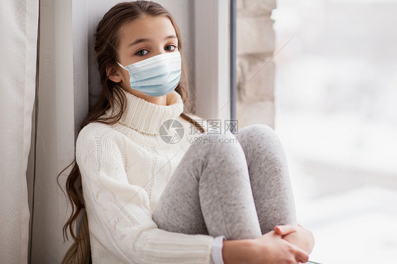 健康安全,检疫大流行悲伤的美丽女孩戴着保护医疗面罩,以防止病疾病,冬天坐家里的窗户上悲伤的女孩戴着医用面具坐图片