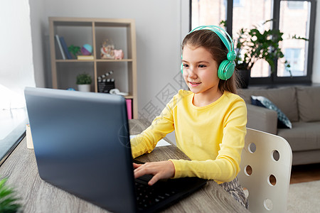 孩子,教育远程学小女孩戴着耳机,家里有笔记本电脑女孩戴着耳机,家里有笔记本电脑图片