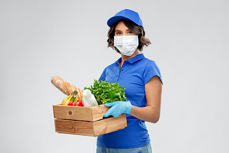 健康保护,安全大流行分娩妇女戴着面罩手套,着装有灰色背景食物的木箱送女人戴口罩,盒子里有食物图片