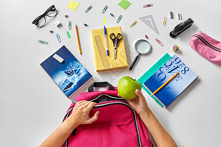 教育学双手包装粉红色背包与绿色苹果,书籍学校用品桌子上手背包,书学用品图片