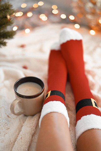 生活方式家庭照片的脚圣诞老人的袜子附近的圣诞树女人坐毯子上,喝热饮料,放松,穿着羊毛袜子热身寒假圣诞节的图片