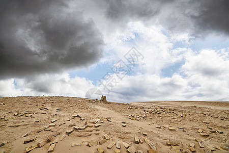多云天气的干燥沙漠中的砖块堆石头图片