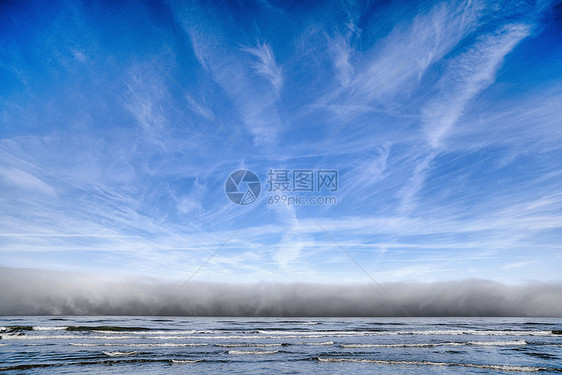 海洋上空多云的天气蓝天下向海岸走来图片