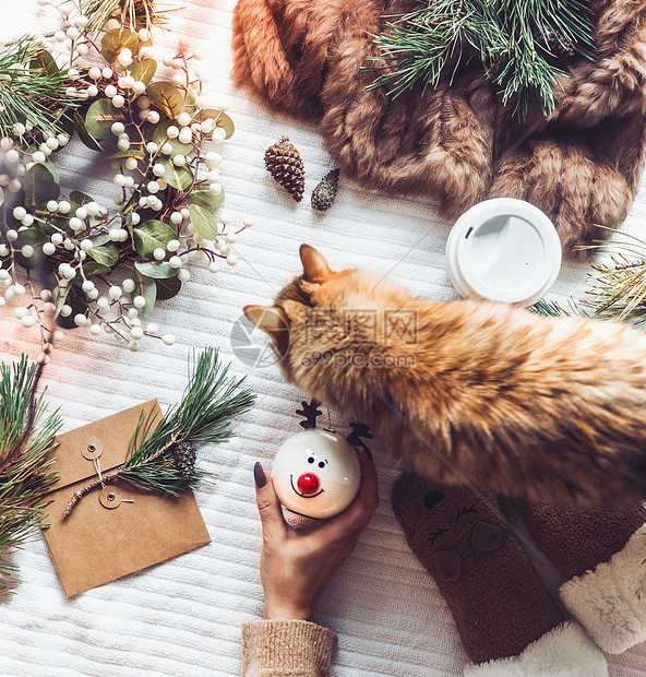 舒适的冬季家居与姜猫女手雪人玩具圣诞节假期准备冷杉枝,毛皮毯,博克,锥上面的风景平躺节日布置圣图片