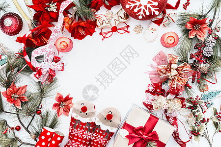 框架由红色圣诞装饰,有趣的鹿袜礼品盒白色背景与冷杉树枝蜡烛上面的风景圣诞背景平躺图片