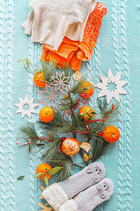 冬天的心情与橘子,橙色的毛衣,有趣的袜子冷杉蓝色针织毛毯与雪花上面的风景平躺图片