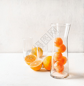 水果冰块橙汁水壶玻璃杯中,用于白色桌子上的提神饮料夏季饮料准备背景图片