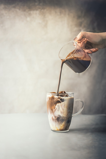 咖啡师手倒咖啡奶油玻璃杯冰咖啡铁乡村桌子混凝土墙背景冰咖啡制作夏季清爽饮料冷饮冰咖啡准备图片