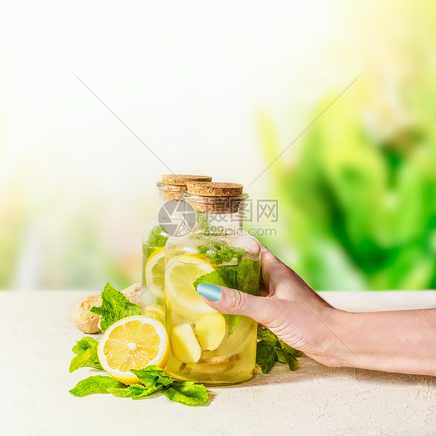 女手瓶姜,柠檬,薄荷柠檬水白色桌子上的绿色自然背景健康的夏季饮料天然免疫助推器注入水果水图片