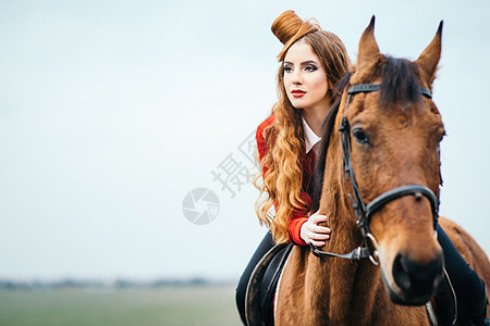 红发骑师女孩穿着红色开衫黑色高靴,带着匹马散步图片
