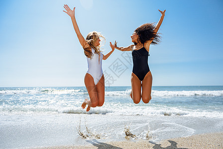 夏天两个穿着泳衣的感女孩热带海滩上跳跃图片