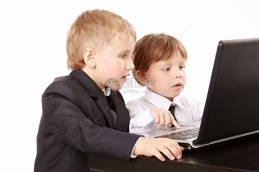 两个穿着西装的小男孩起看着笔记本电脑的屏幕,图片