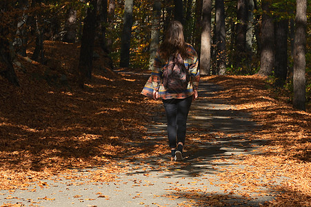 个带着背包的年轻女孩正穿过秋天的森林图片